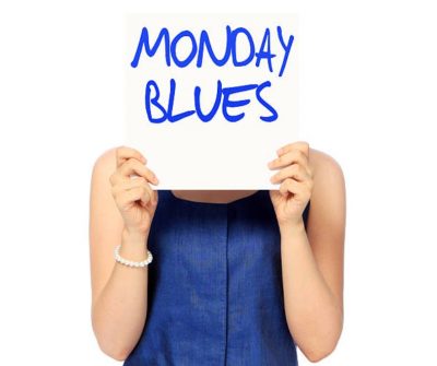 Woman holding a sign in front of her face. The sign reads 'Monday blues'